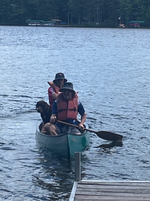 Photo of two men and a dog in a canoe from the front view.