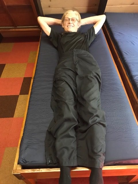 photo of an older woman lying on a new mattress in a murphy bed cot.