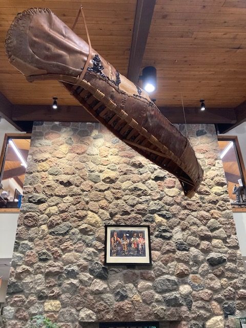 photo of a traditional canoe hanging from the ceiling.  The canoe is made of wood and rawhide.