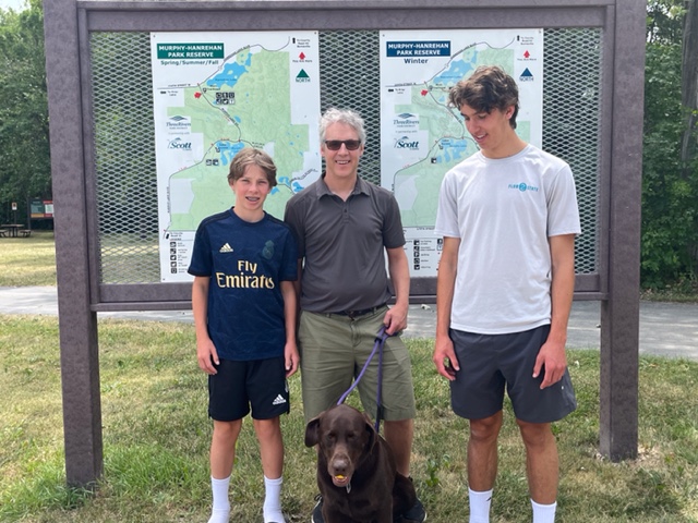 Photo of the boys in the family with Rey in front of the park map.