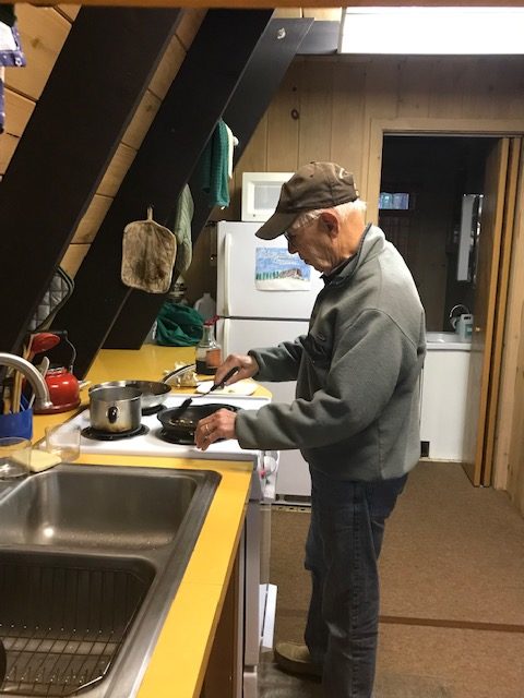 photo of man in a hat cooking pancakes on the stovetop