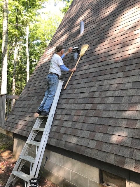 photo of man on ladder leaning against a roof.