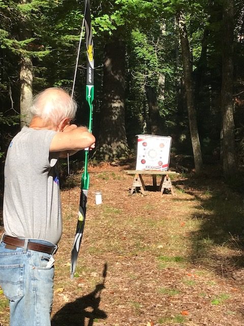 photo of man shooting a bow an arrow at an archery target