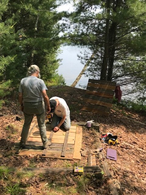 man and woman repair pier boards on dry land.