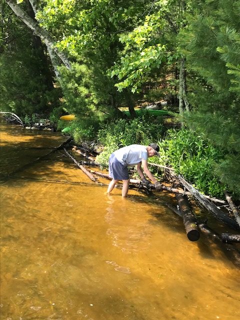 photo of man securing logs horizontally to protect the lake shoreline from waves