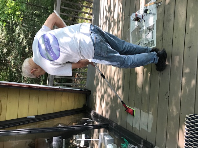 man cleaning deck to reveal original wood