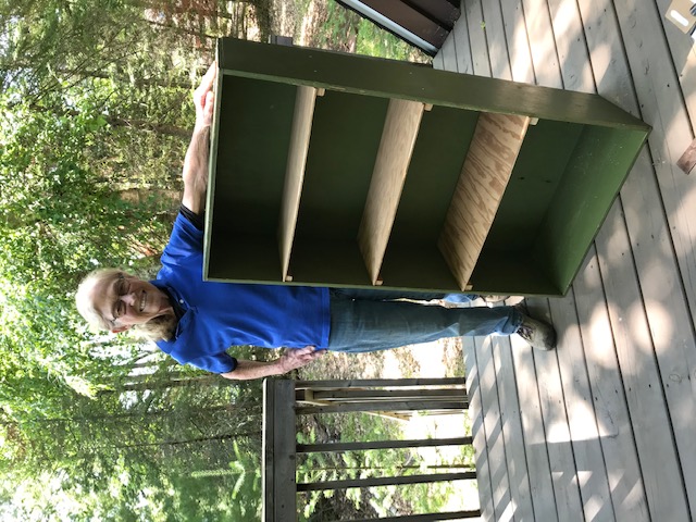 woman standing next to the finished green box with shelves