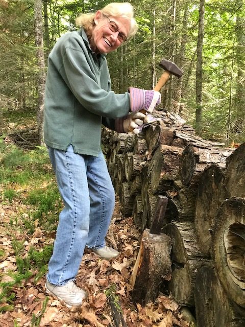 woman hold sledge hammer in front of log pile