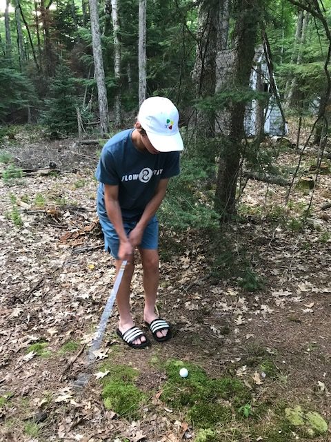 teenage bog playing golf in the woods