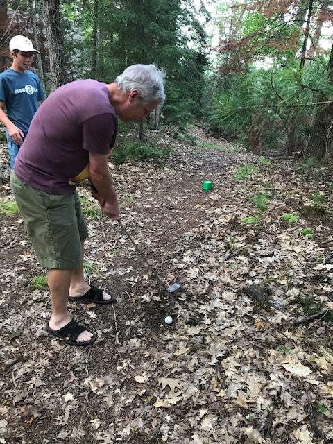 older man playing golf in woods