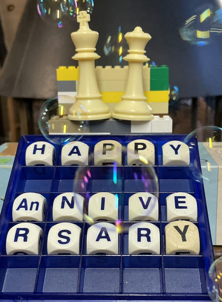 photo of King and Queen Chess pieces  and a Boogle Board with the words Happy Anniversary spelled out.