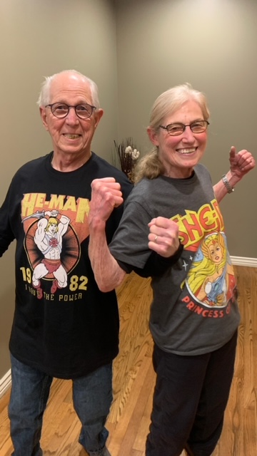 photo older man and woman in he-man and she-ra t-shirts