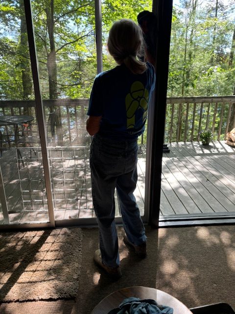 woman cleaning windows on inside by hand.