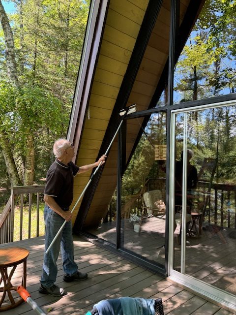 man cleaning windows of a-frame on outside