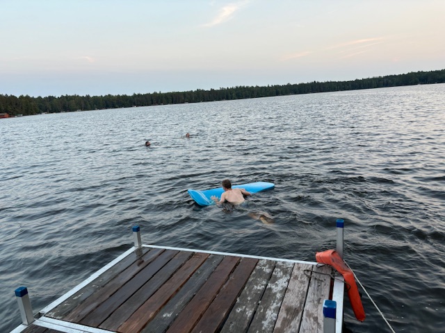 three people swimming in lake