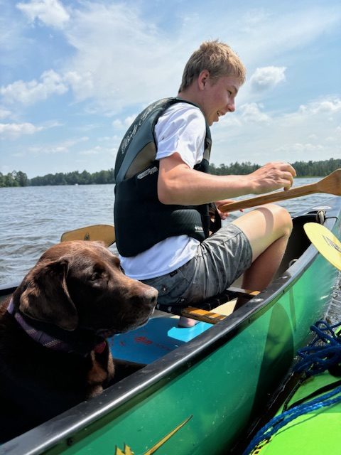 photo of boy and dog in canoe