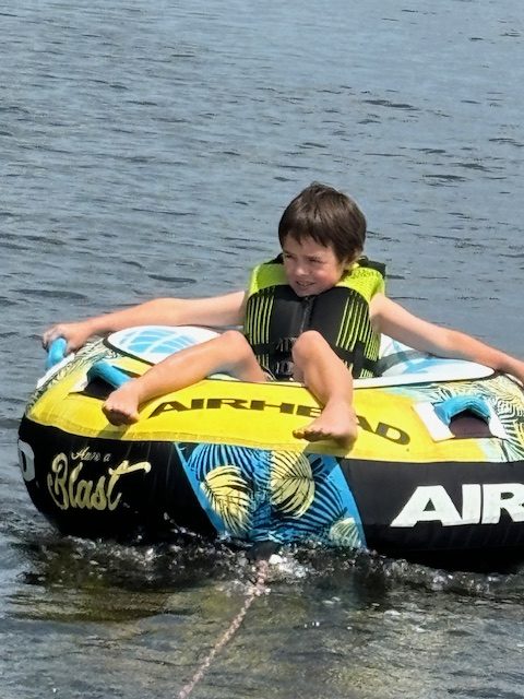 child on tube behind boat