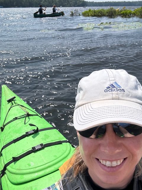 woman taking selfie on kayak with canoe in background