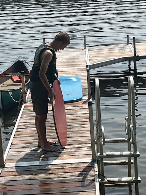 boy with circle board on dock at lake.