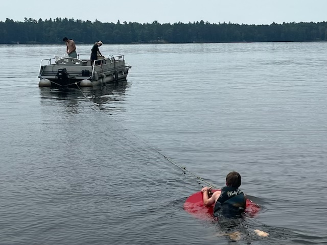 boy getting ready to circle board behind pontoon boat