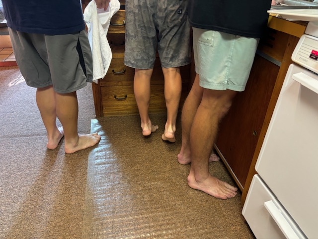 photo of the legs and feet of three men doing dishes.