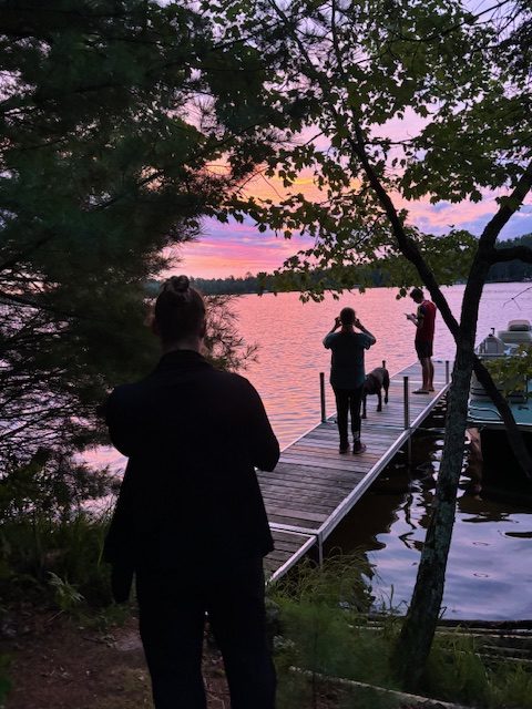 photo of people on doc taking photos of sunrise on the lake