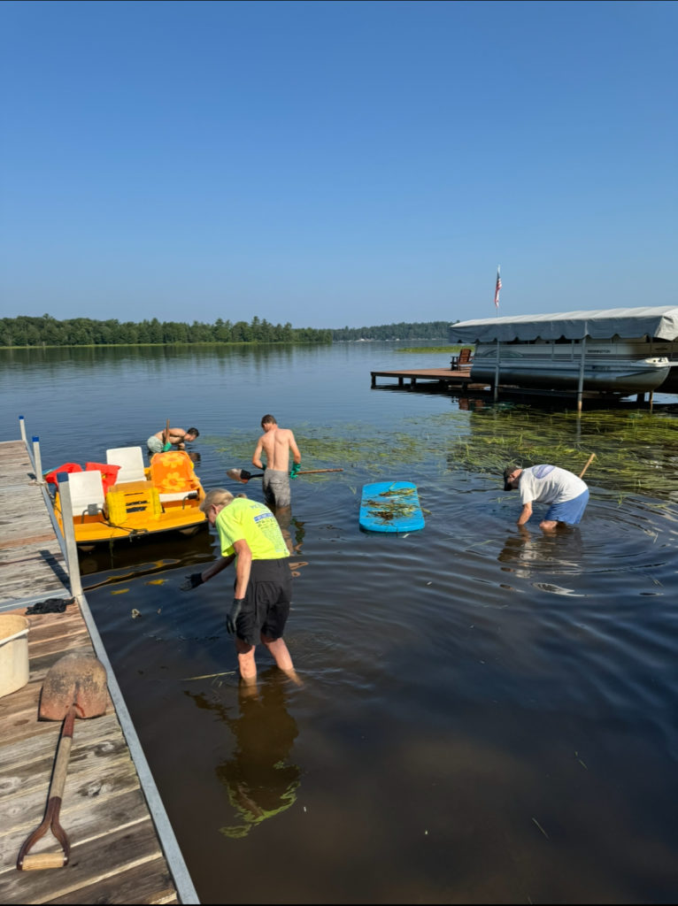 three men and woman removing weeds from lake