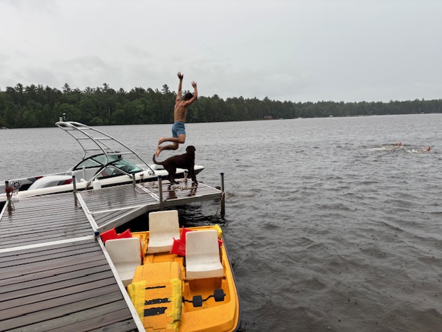 boy jumping off dock with Rey anxiously looking on